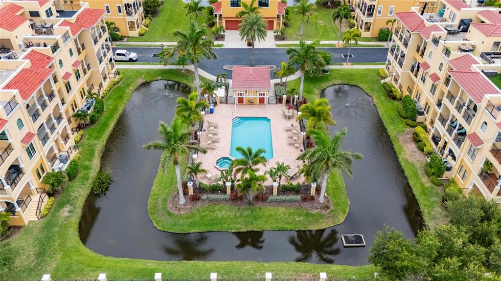 An aerial view shows a swimming pool and hot tub surrounded by a small pond — 6408 MAYRA SHORES LANE, APOLLO BEACH, FL