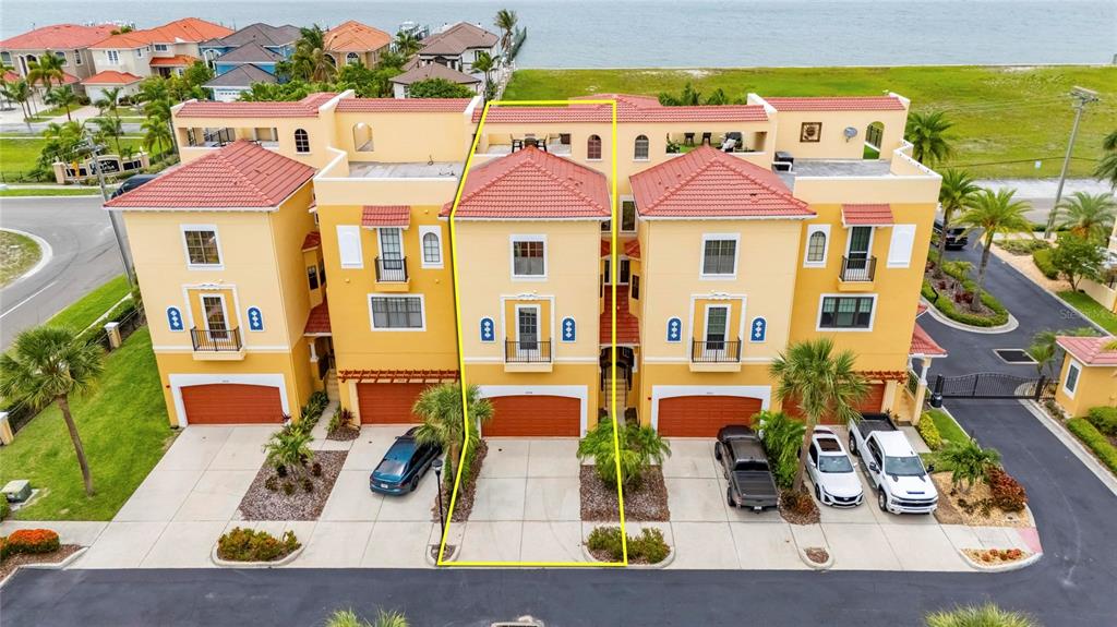 An aerial view shows a yellow three-story townhouse with a red tile roof — 6408 MAYRA SHORES LANE, APOLLO BEACH, FL