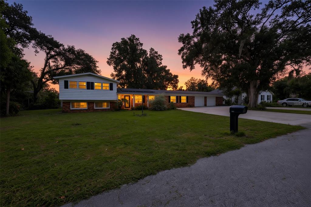 A split-level house with a brick and white siding exterior sits on a grassy lot — 401 OVERLAND DRIVE, BRANDON, FL