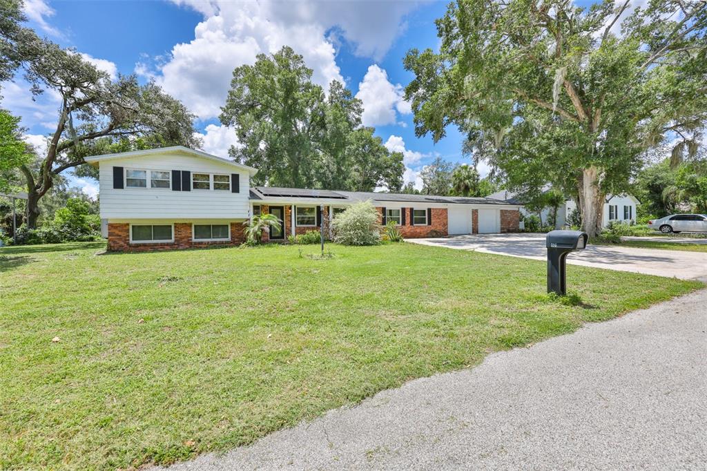 A split-level house with a brick and white siding exterior sits on a grassy lot — 401 OVERLAND DRIVE, BRANDON, FL