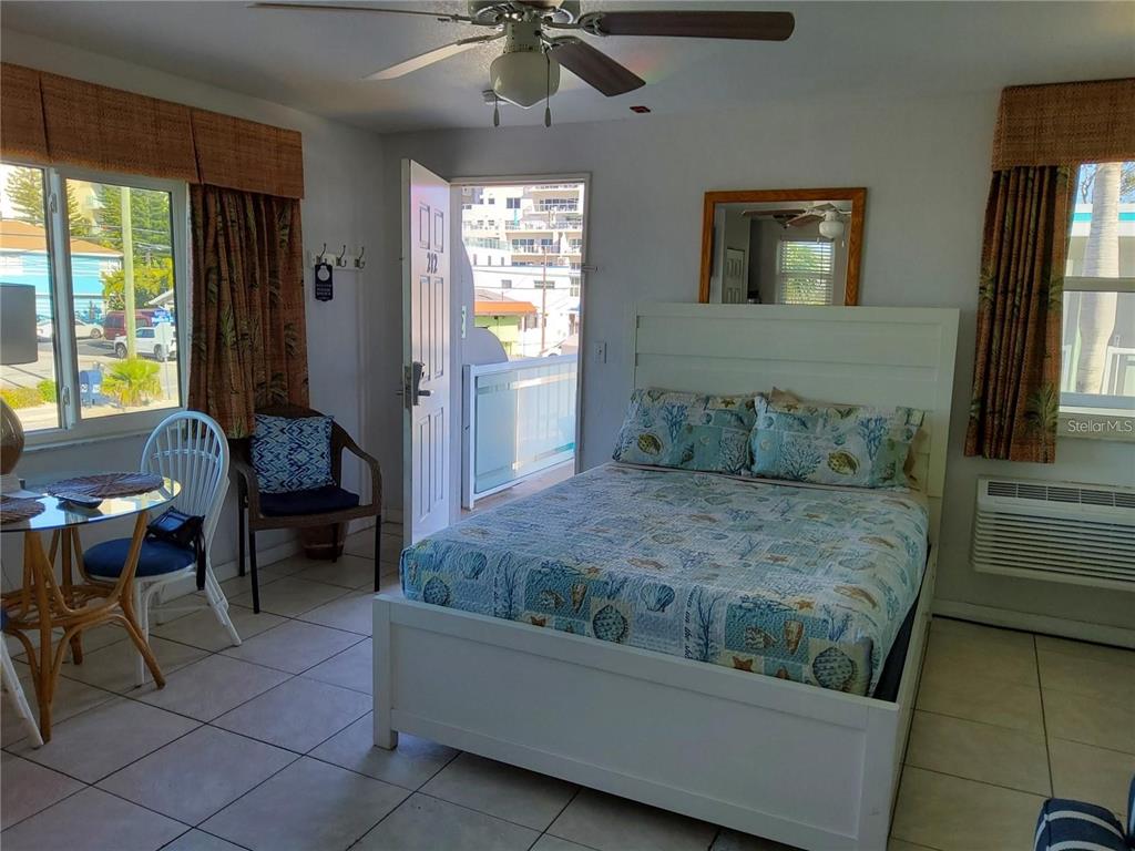 A bedroom with tile floors, a white bed frame, a ceiling fan, and a balcony door — 603 MANDALAY AVENUE UNIT 212, CLEARWATER, FL