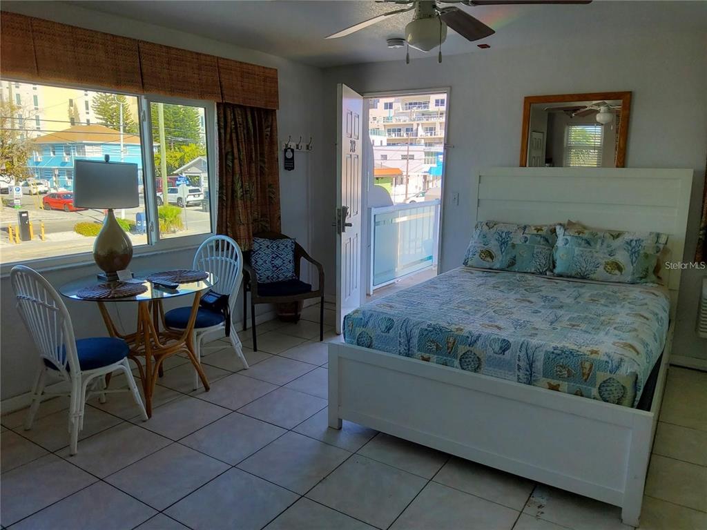 A bedroom with a bed, a small dining table, and a door opening to a balcony — 603 MANDALAY AVENUE UNIT 212, CLEARWATER, FL