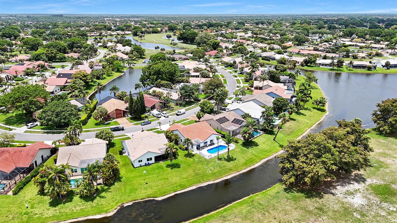 An aerial view of a suburban neighborhood featuring houses with pools along a canal — 10131 Camelback Lane, Boca Raton FL 33498, BOCA RATON, FL