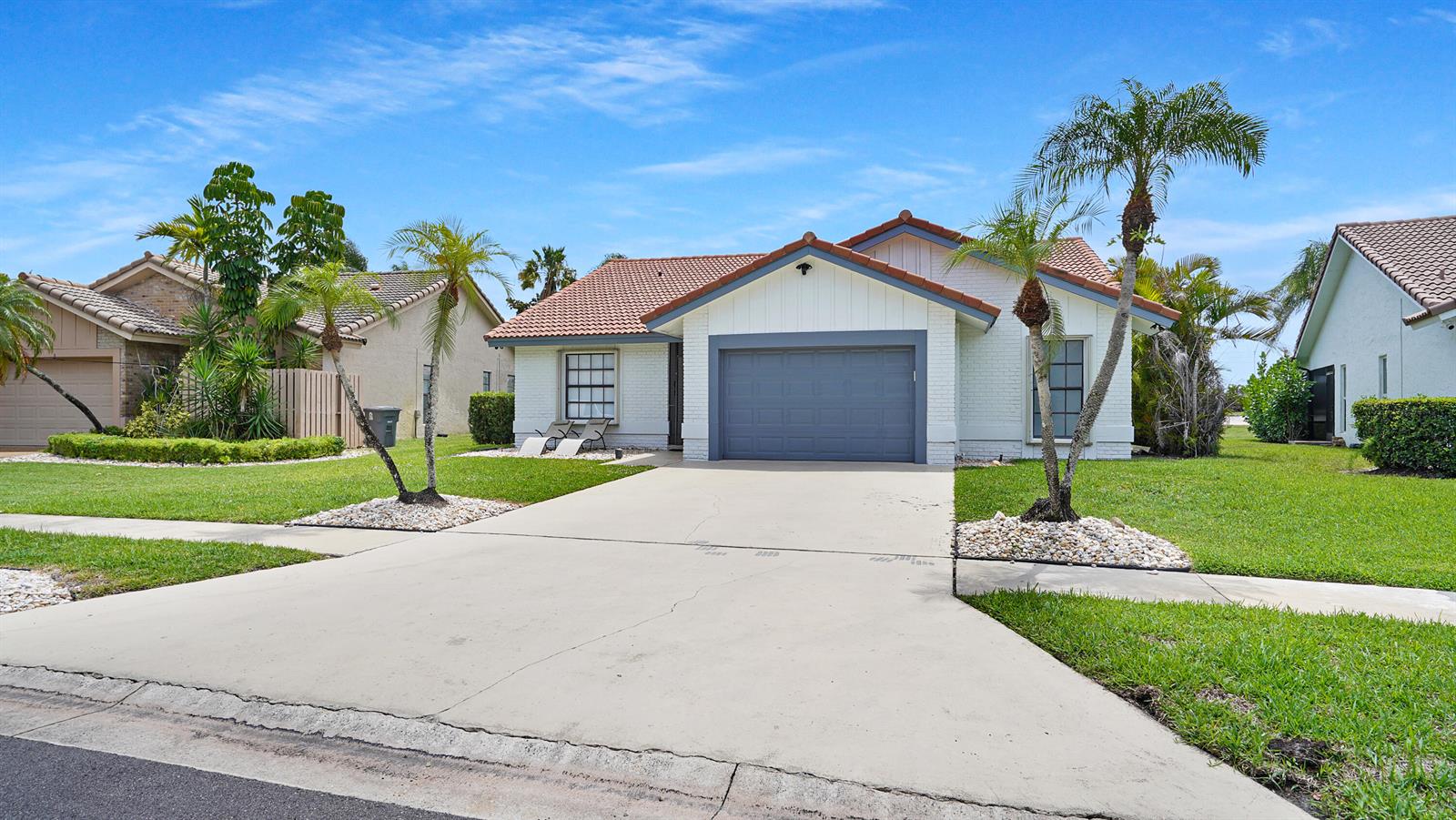 A single-story house with a white brick exterior, gray garage door, and palm trees — 10131 Camelback Lane, Boca Raton FL 33498, BOCA RATON, FL