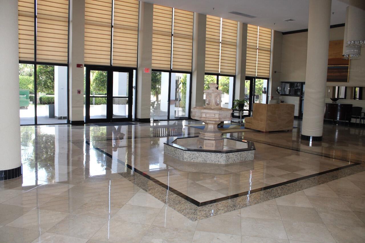 A bright lobby features a stone fountain, polished tile floors, and floor-to-ceiling windows with blinds — 1010 S Ocean Boulevard # 1214, Pompano Beach FL 33062, POMPANO BEACH, FL
