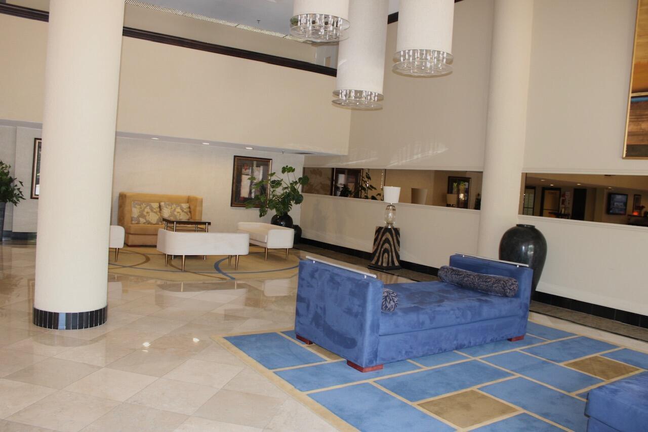 A hotel lobby features a blue velvet chaise lounge, white seating, and tall cylindrical chandeliers — 1010 S Ocean Boulevard # 1214, Pompano Beach FL 33062, POMPANO BEACH, FL