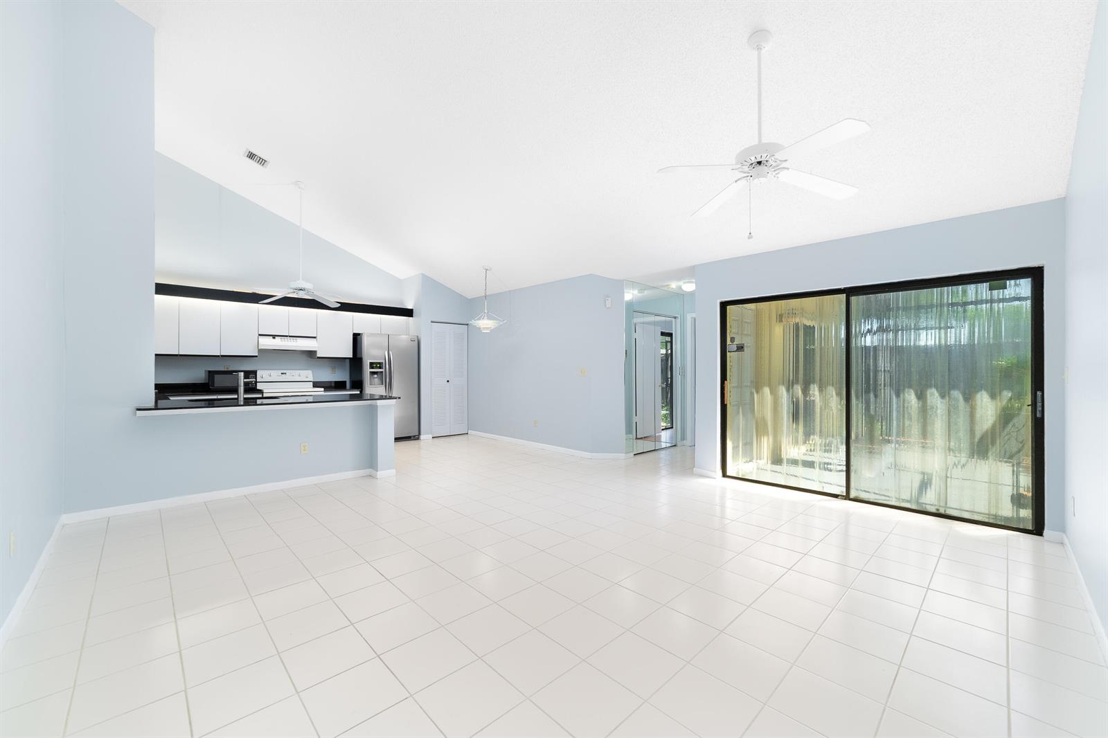 A bright, open-concept living and dining area with white tile floors and a modern kitchen — 1139 Summit Trail Circle # A, West Palm Beach FL 33415, WEST PALM BEACH, FL