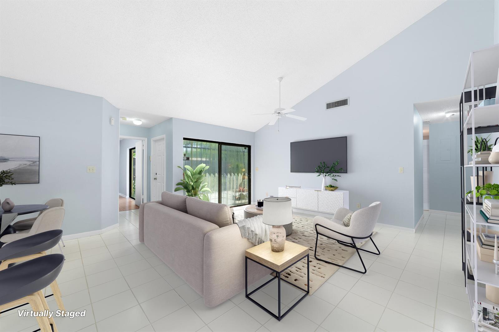 A virtually staged living room features light blue walls, white tile floors, and a vaulted ceiling — 1139 Summit Trail Circle # A, West Palm Beach FL 33415, WEST PALM BEACH, FL