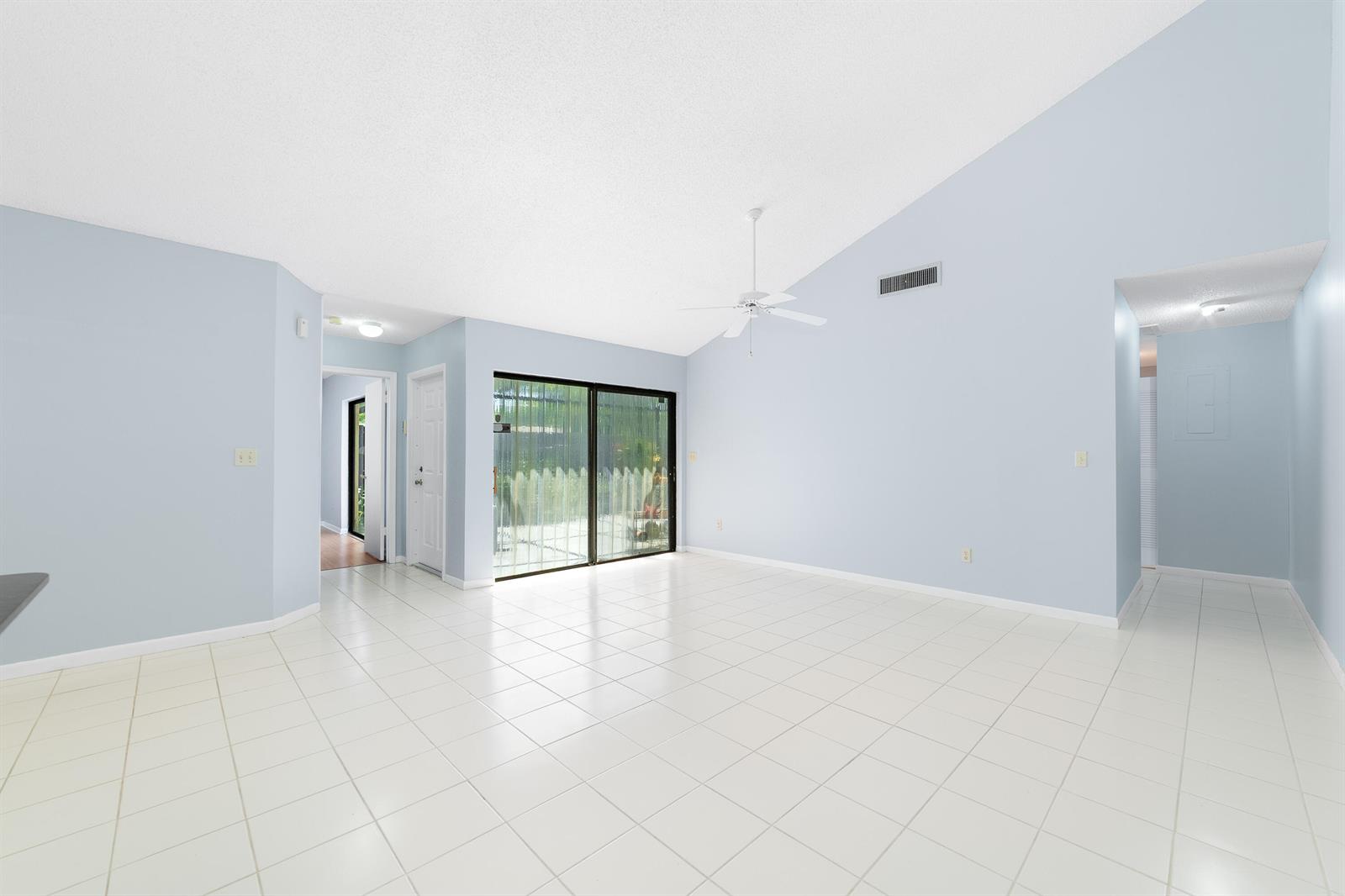 A bright living room with light blue walls, white tile flooring, and a vaulted ceiling — 1139 Summit Trail Circle # A, West Palm Beach FL 33415, WEST PALM BEACH, FL