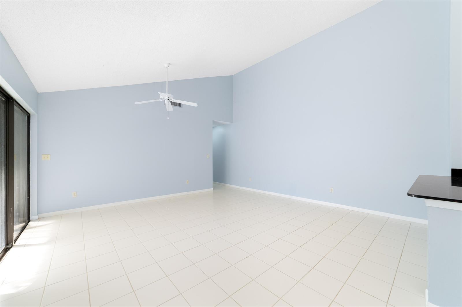An empty room with light blue walls, white tile flooring, and a vaulted ceiling — 1139 Summit Trail Circle # A, West Palm Beach FL 33415, WEST PALM BEACH, FL