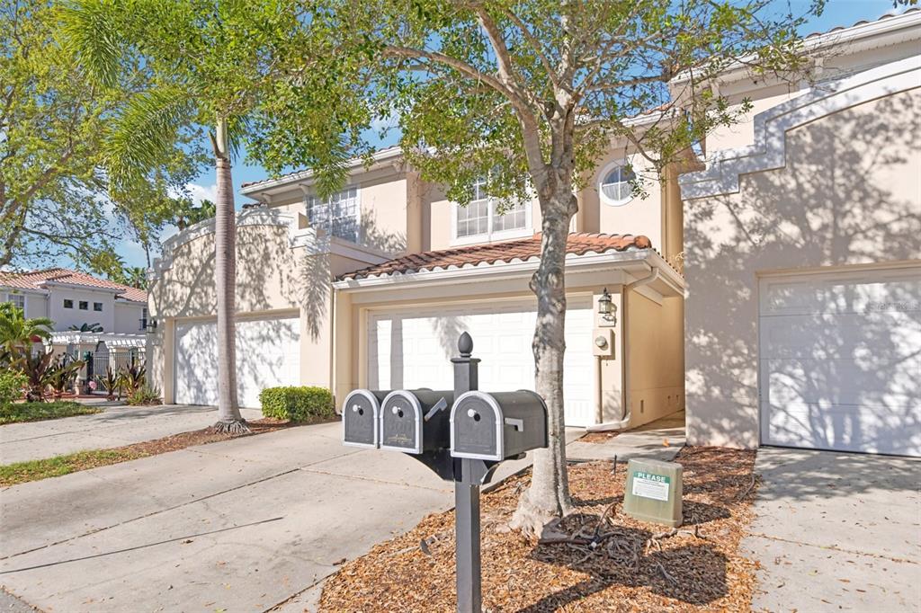 A two-story townhouse exterior with a two-car garage, a mailbox post, and a tree — 300 VALENCIA CIRCLE, ST PETERSBURG, FL