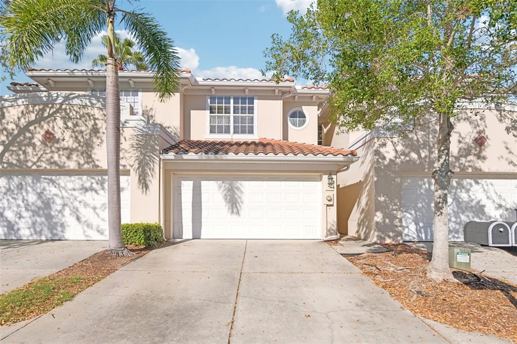 A two-story townhouse exterior with a beige stucco facade, tile roof, and a garage — 300 VALENCIA CIRCLE, ST PETERSBURG, FL