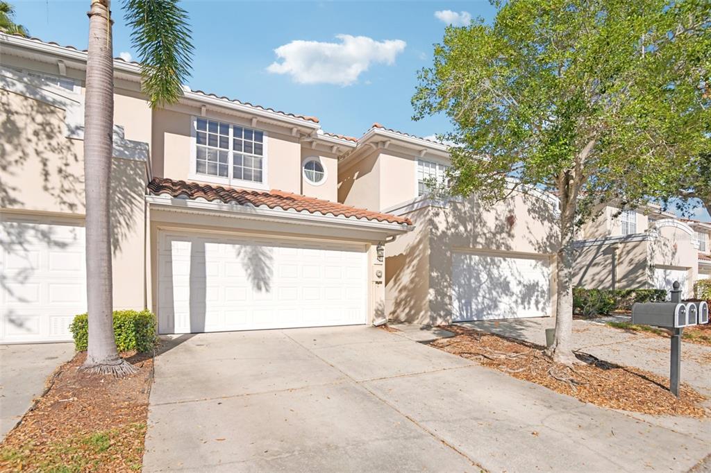 A two-story townhouse with a beige stucco exterior, tile roof, and two attached garages — 300 VALENCIA CIRCLE, ST PETERSBURG, FL