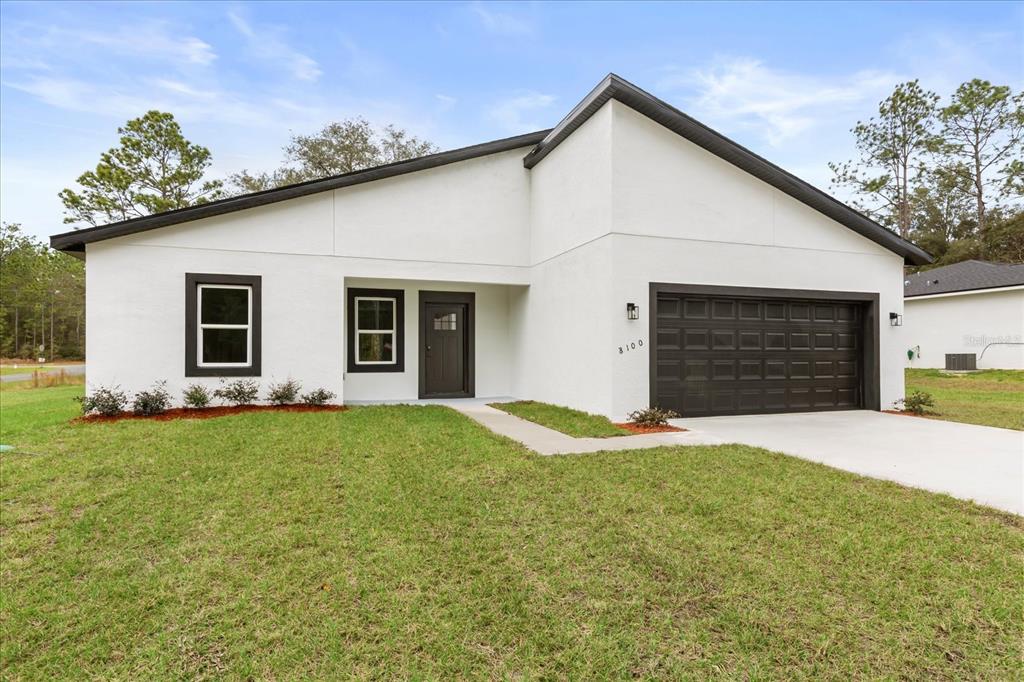 A modern, white single-story house with a dark garage door and dark window trim — 8100 N TINY LILY DRIVE, CITRUS SPRINGS, FL