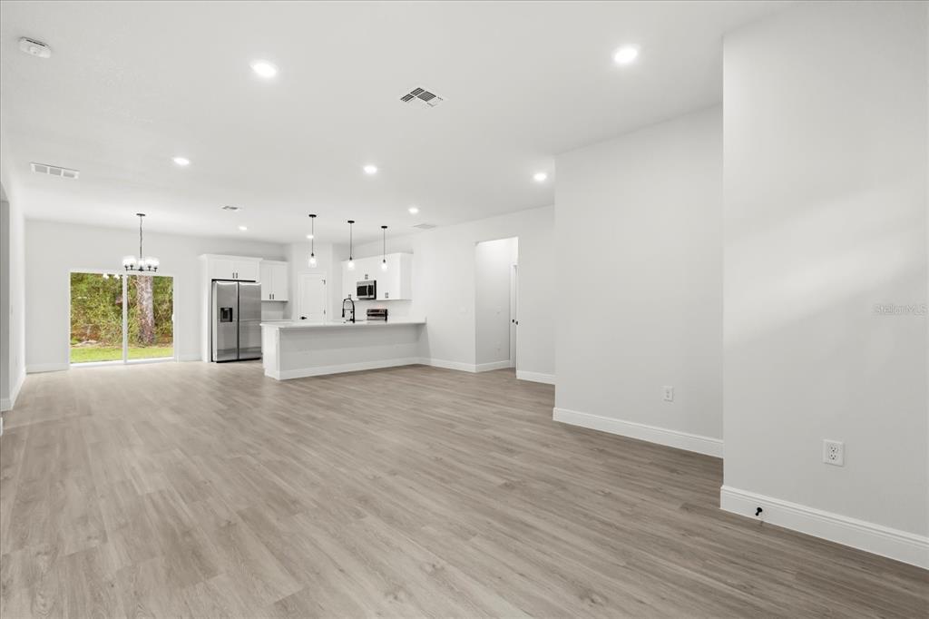 An open-concept kitchen and living area features light wood-look flooring, white cabinetry, and recessed lighting — 8100 N TINY LILY DRIVE, CITRUS SPRINGS, FL
