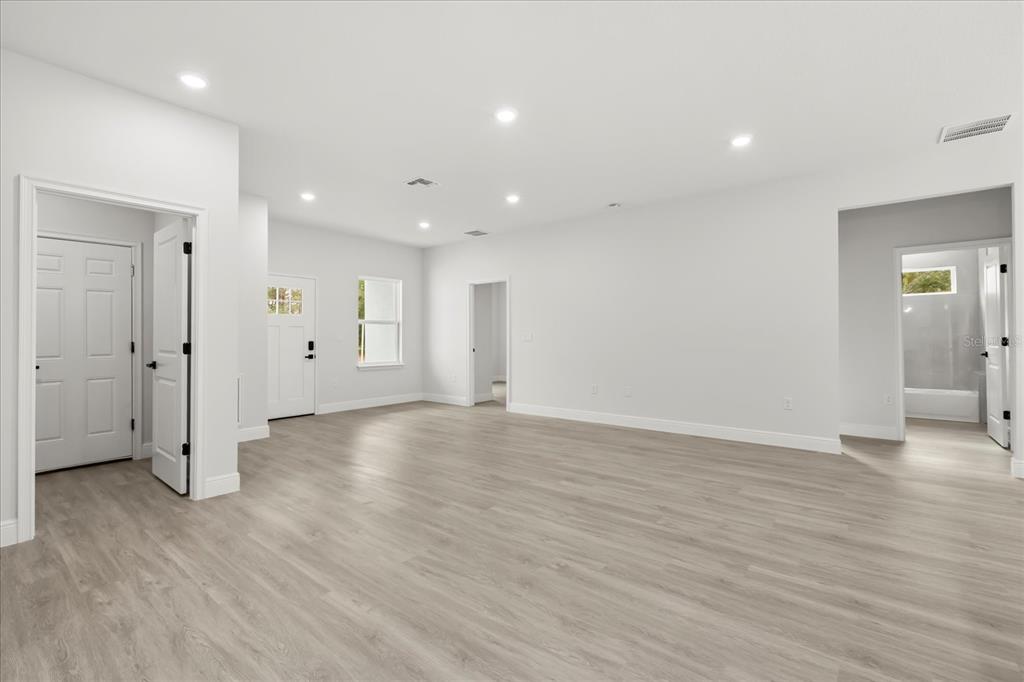 An empty room with light wood-look flooring, white walls, recessed lighting, and several doorways — 8100 N TINY LILY DRIVE, CITRUS SPRINGS, FL