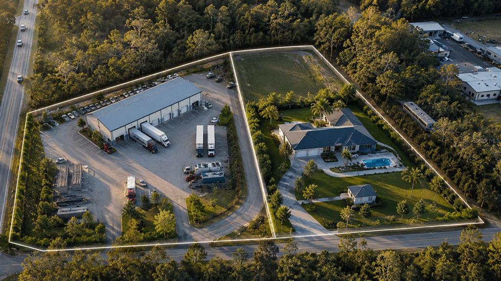 An aerial view shows a commercial warehouse property adjacent to a residential home with a pool — 6518 OLD TAMPA HIGHWAY UNIT A, DAVENPORT, FL