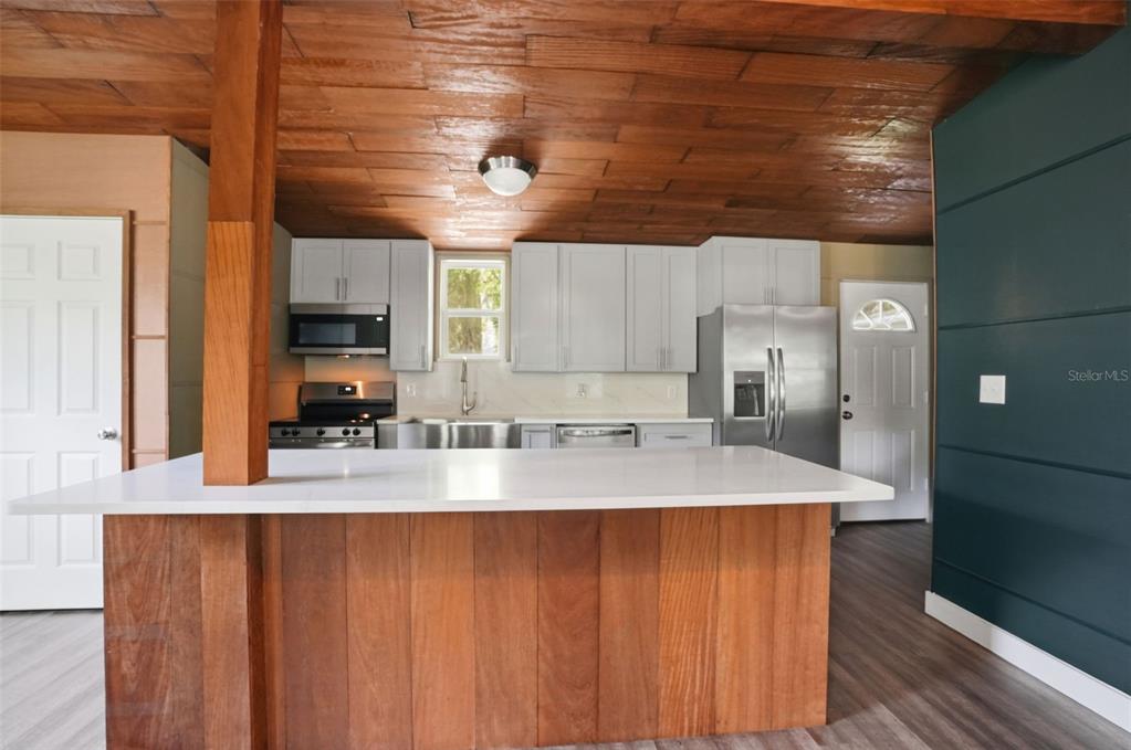 A kitchen features a wooden ceiling, white cabinets, a large island, and stainless steel appliances — 320 S OTIS AVENUE, LECANTO, FL