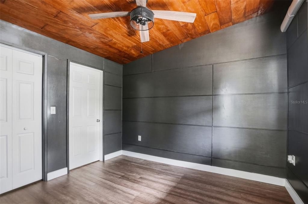A room features dark paneled walls, a wood-plank ceiling, a ceiling fan, and wood flooring — 320 S OTIS AVENUE, LECANTO, FL