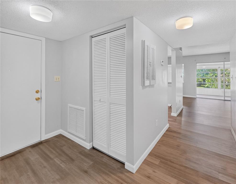 An entryway with light gray walls, wood-look flooring, and a white louvered closet door — 600 FAIRWAYS CIRCLE UNIT B, OCALA, FL