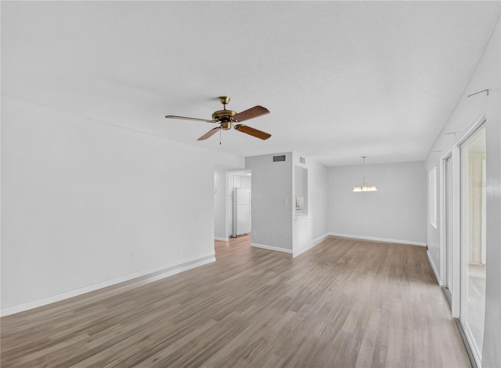An open-concept living and dining area features light wood-look flooring and a ceiling fan — 600 FAIRWAYS CIRCLE UNIT B, OCALA, FL