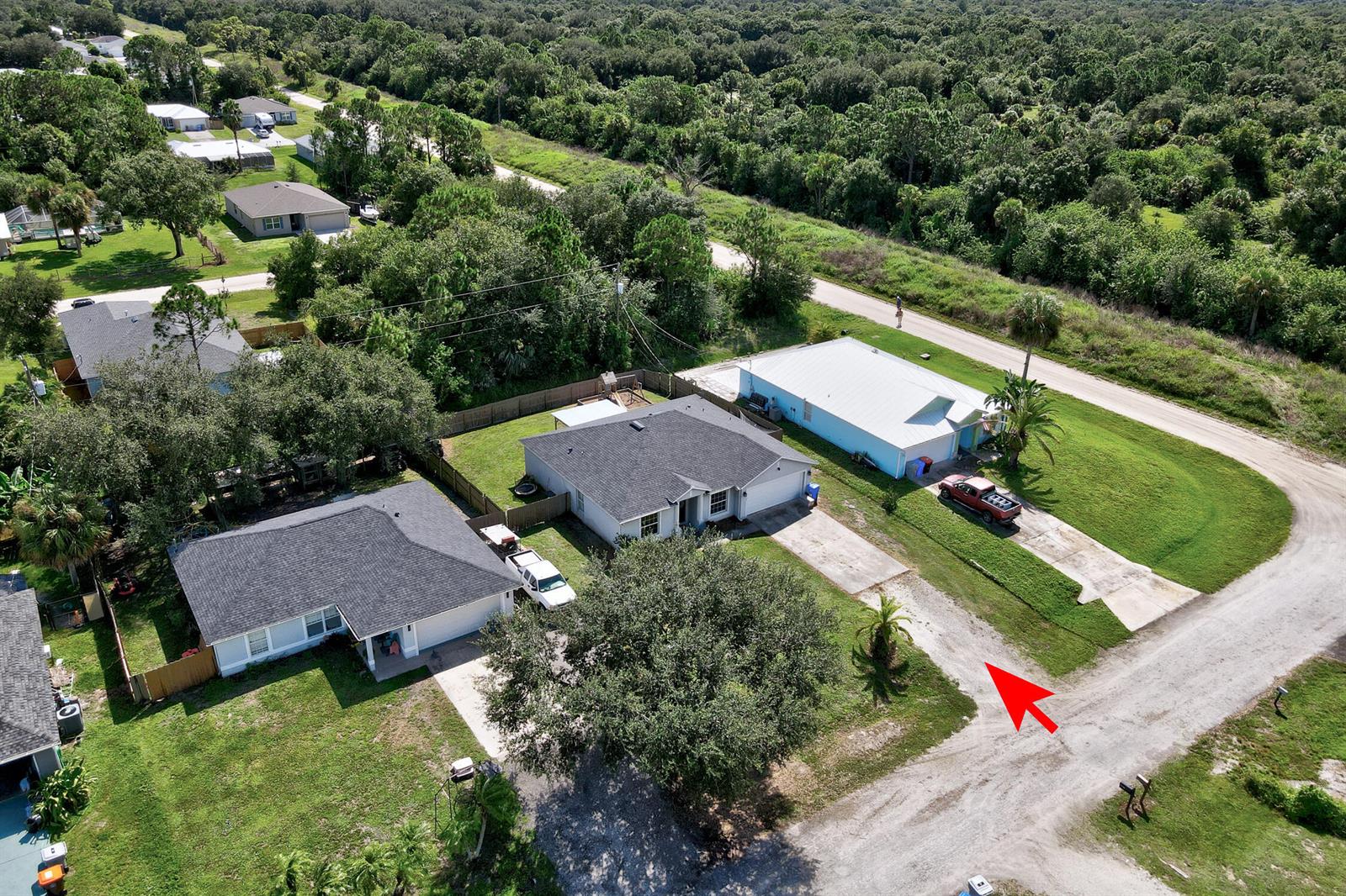 A single-story gray house with a two-car garage and a front lawn under a blue sky — 7726 102nd Avenue, Vero Beach FL 32967, VERO BEACH, FL