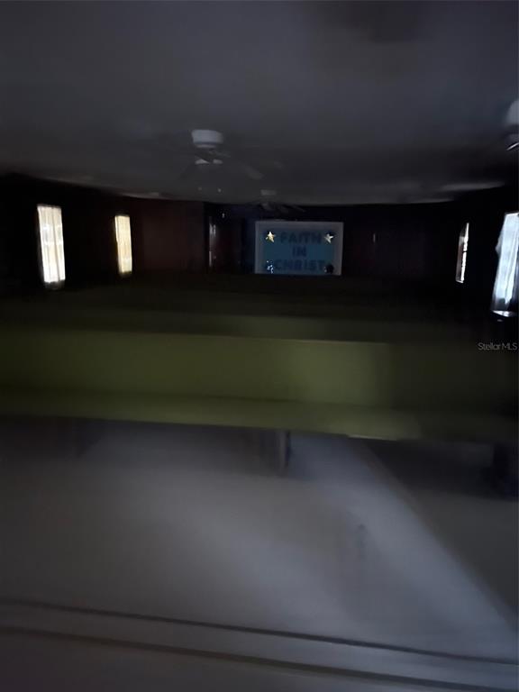A dimly lit room features rows of pews facing a sign that reads Faith in Christ — 1235 SAGE STREET, MONTICELLO, FL