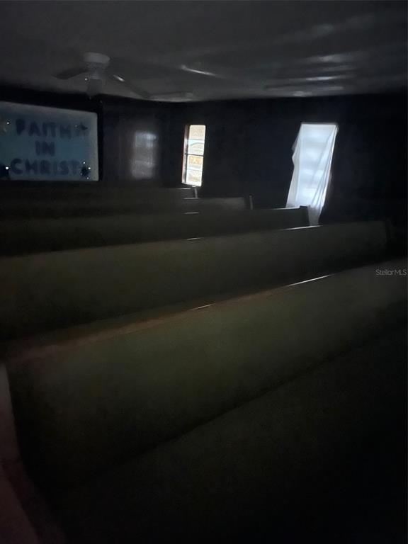 A dimly lit room features rows of wooden pews and a sign reading Faith in Christ — 1235 SAGE STREET, MONTICELLO, FL