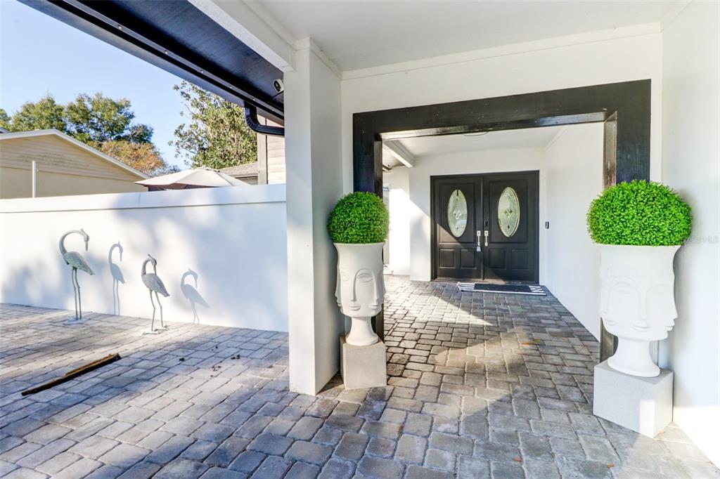 A paved entryway features two large face-shaped planters and a double door with oval glass — 16212 W COURSE DRIVE, TAMPA, FL
