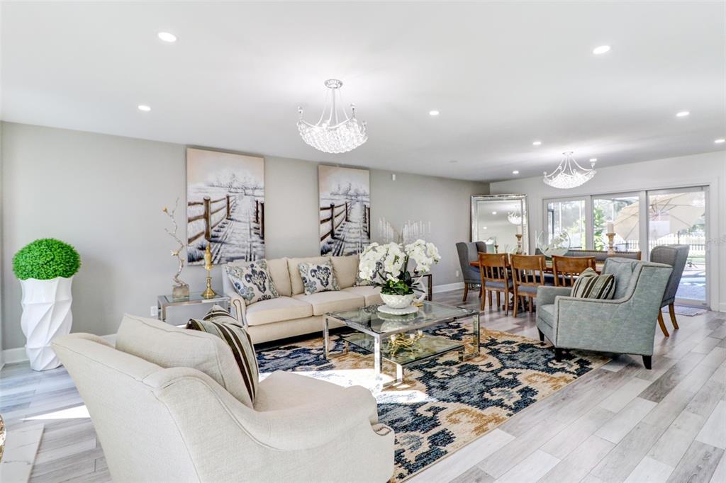A living room features a beige sofa, patterned area rug, and two crystal chandeliers — 16212 W COURSE DRIVE, TAMPA, FL