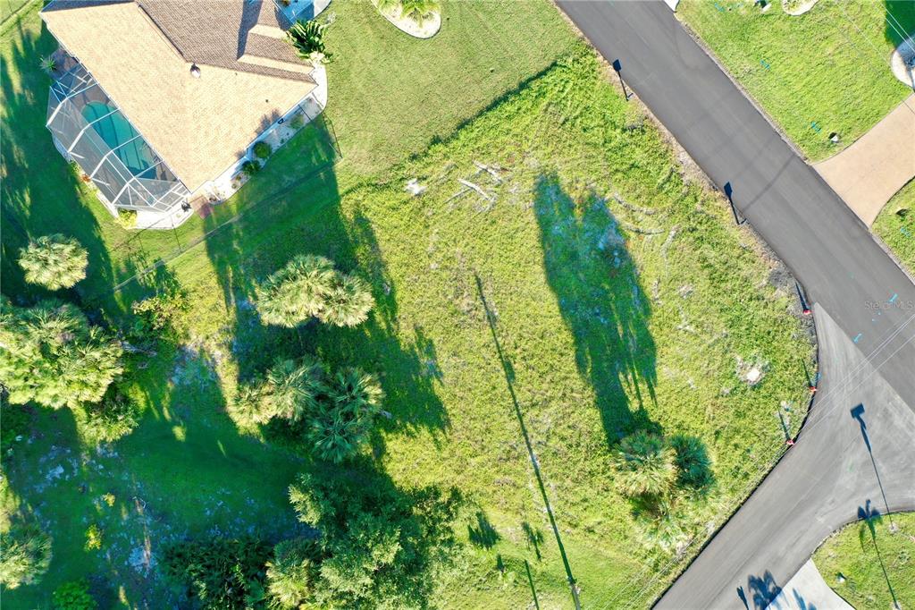 An aerial view shows a vacant, grassy residential lot bordered by a paved road and house — 2 SPORTSMAN WAY, ROTONDA WEST, FL