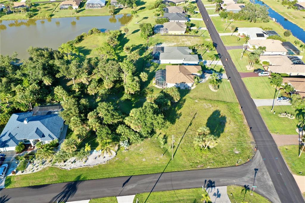 An aerial view shows a residential neighborhood with houses, a pond, and a vacant lot — 2 SPORTSMAN WAY, ROTONDA WEST, FL