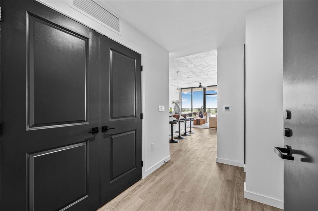 An entryway with black double doors leads to an open-concept living area with wood flooring — 221 MAIN STREET N UNIT B3-716, ST PETERSBURG, FL