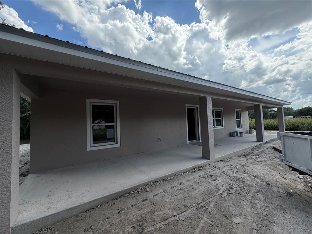 A view of a house exterior featuring a long covered concrete porch and stucco walls — 8115 SW EASY STREET, ARCADIA, FL