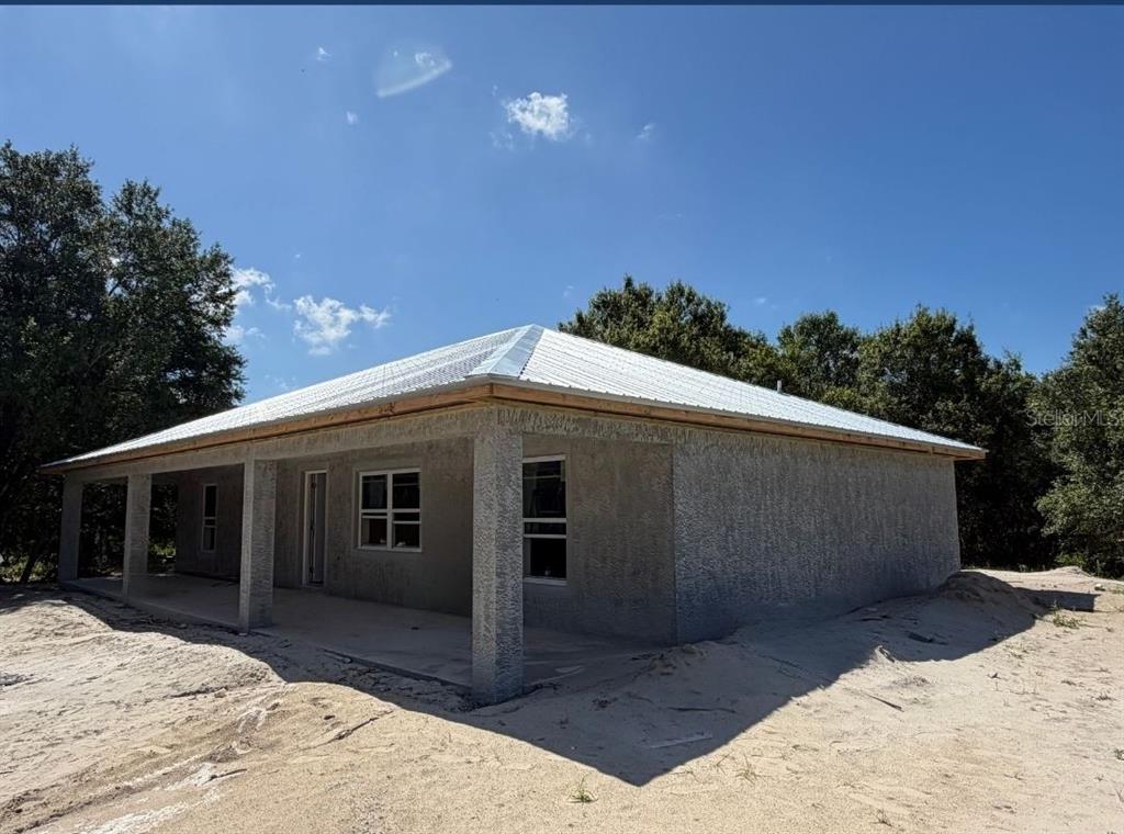 A single-story house under construction with a metal roof, stucco exterior, and a covered porch — 8115 SW EASY STREET, ARCADIA, FL