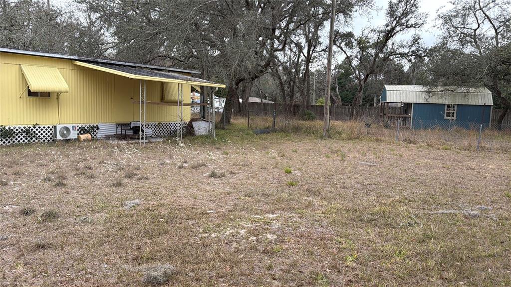 A yellow mobile home with a metal awning stands next to a blue storage shed — 12013 BETHWOOD AVENUE, NEW PORT RICHEY, FL