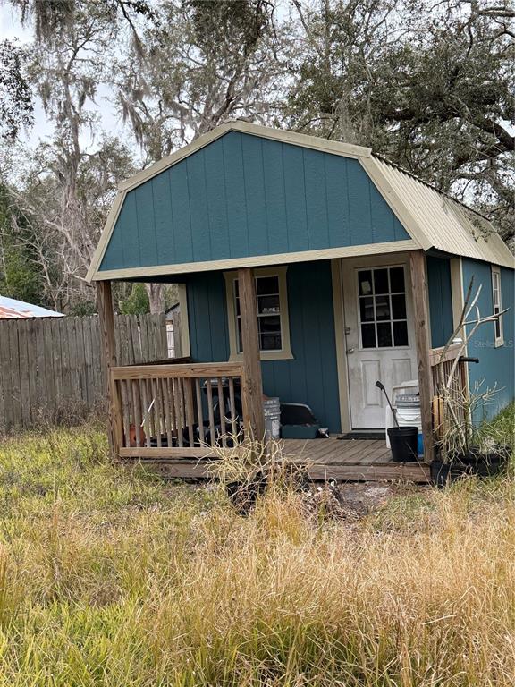 A blue wooden shed with a small front porch sits in a grassy yard — 12013 BETHWOOD AVENUE, NEW PORT RICHEY, FL