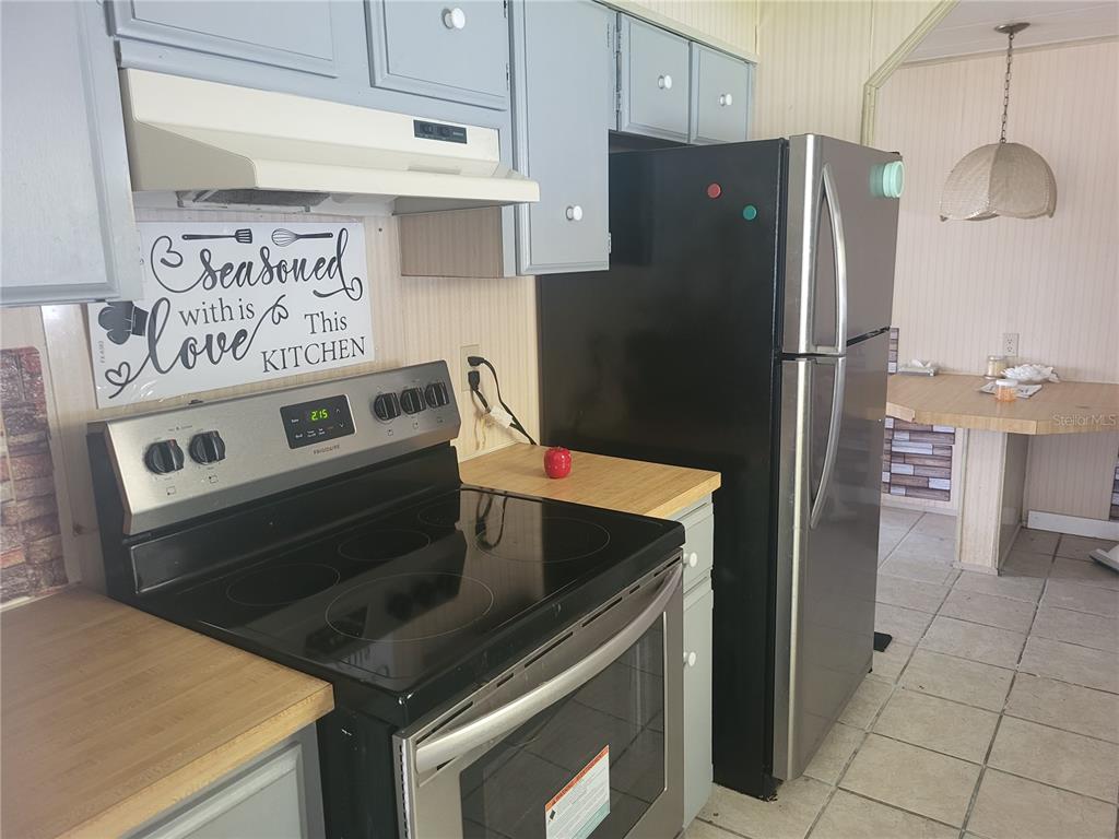 A kitchen features grey cabinets, a black electric stove, and a stainless steel refrigerator — 357 BADGER LANE, HAINES CITY, FL