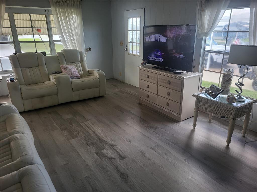 A living room features light wood-look flooring, white leather recliners, and a television on a dresser — 357 BADGER LANE, HAINES CITY, FL