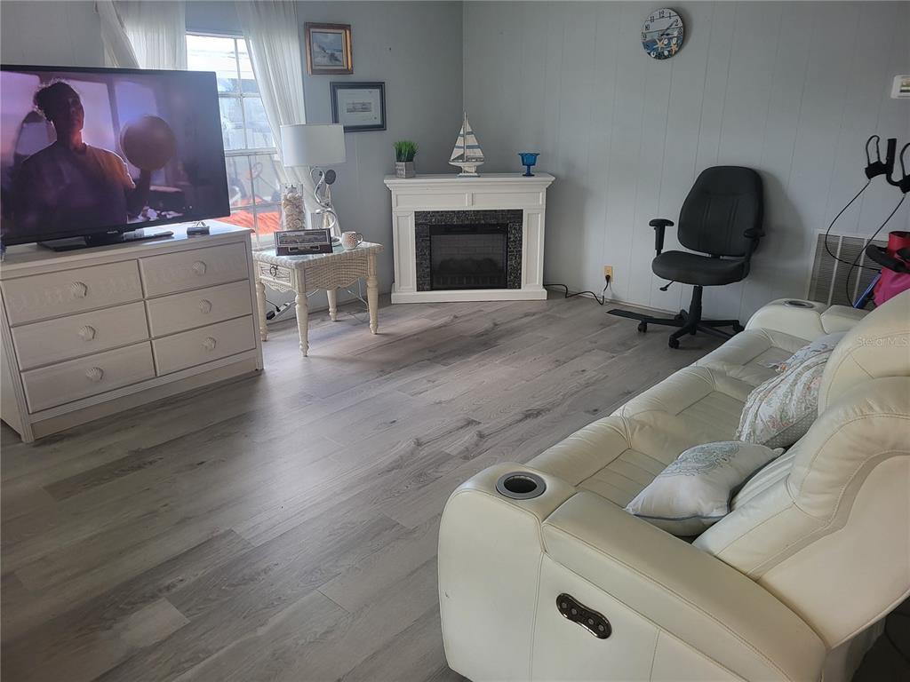 A living room features a white dresser with a television, a fireplace, and a white sofa — 357 BADGER LANE, HAINES CITY, FL