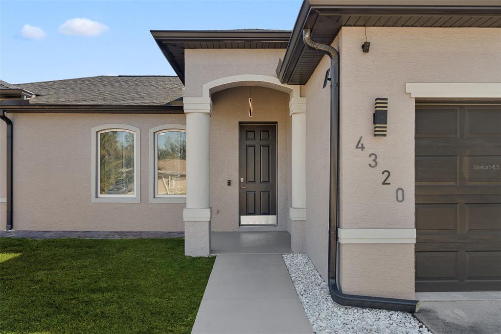 The exterior of a house features a dark front door, arched windows, and address numbers — 4320 MICHALER STREET, NORTH PORT, FL