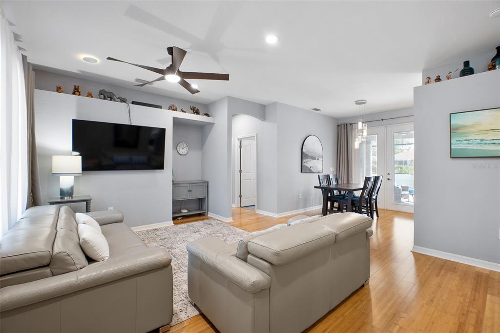 A living room with light gray walls, hardwood floors, a ceiling fan, and a dining area — 4320 MICHALER STREET, NORTH PORT, FL