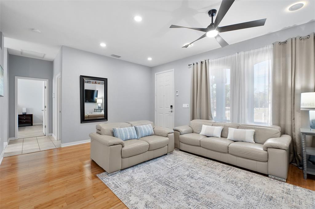 A living room features light gray walls, hardwood floors, a ceiling fan, and two sofas — 4320 MICHALER STREET, NORTH PORT, FL