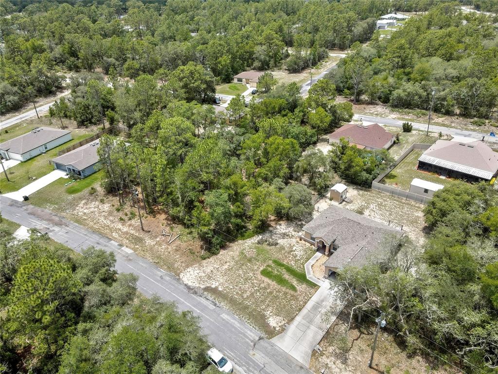 An aerial view shows a suburban house with a driveway surrounded by trees and lots — 9652 N SAN JOSE WAY, CITRUS SPRINGS, FL