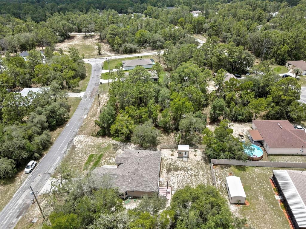 An aerial view shows a residential property with a house, shed, and pool among trees — 9652 N SAN JOSE WAY, CITRUS SPRINGS, FL