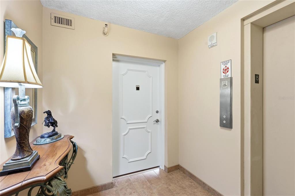 An entryway features a white door, a console table with a lamp, and an elevator — 770 S PALM AVENUE UNIT 1501, SARASOTA, FL