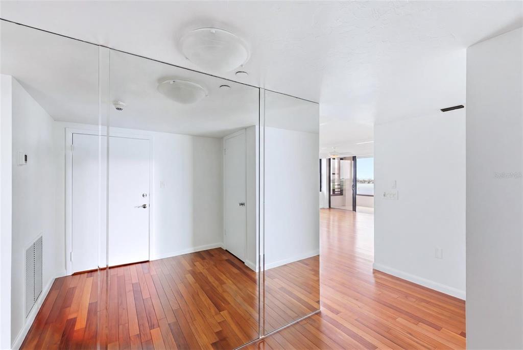An entryway with hardwood floors, mirrored closet doors, and a view into a living area — 770 S PALM AVENUE UNIT 1501, SARASOTA, FL