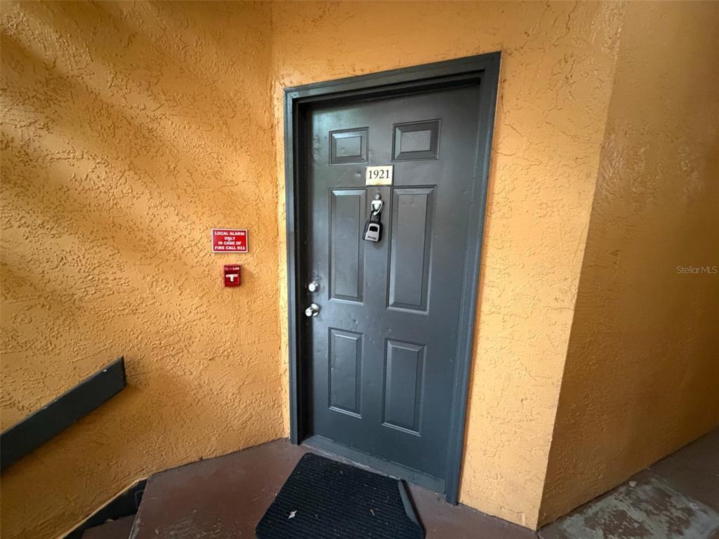 A dark gray apartment door with the number 1921 is set in a textured orange wall — 4518 COMMANDER DRIVE UNIT 1921, ORLANDO, FL