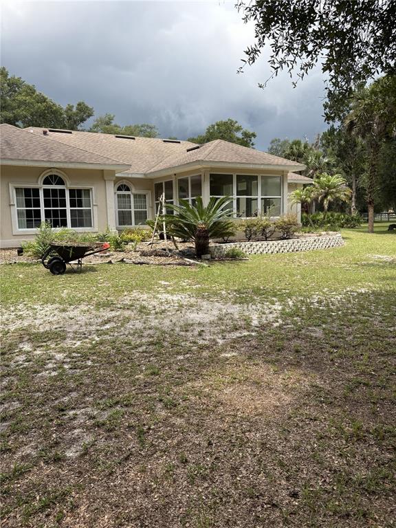 The exterior of a beige house features a screened-in porch and a landscaped garden bed — 155 BLAKE STREET, PIERSON, FL