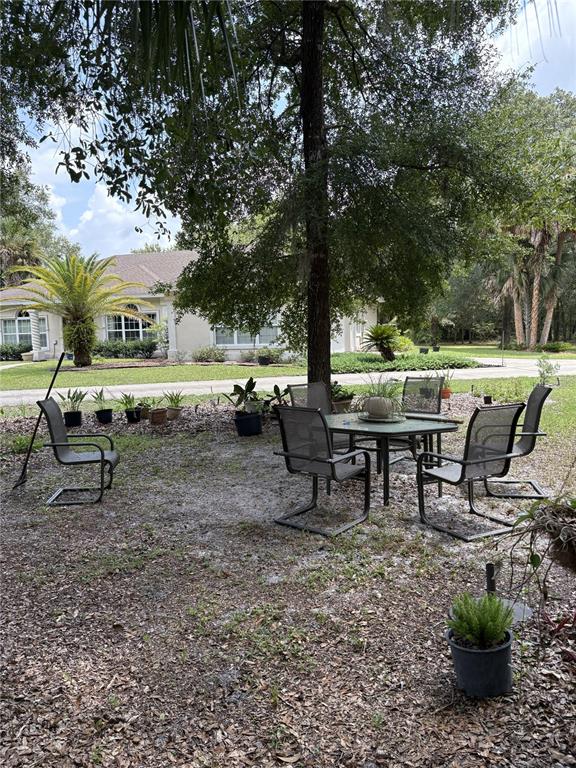A patio area with a table and chairs sits under a large tree in a yard — 155 BLAKE STREET, PIERSON, FL